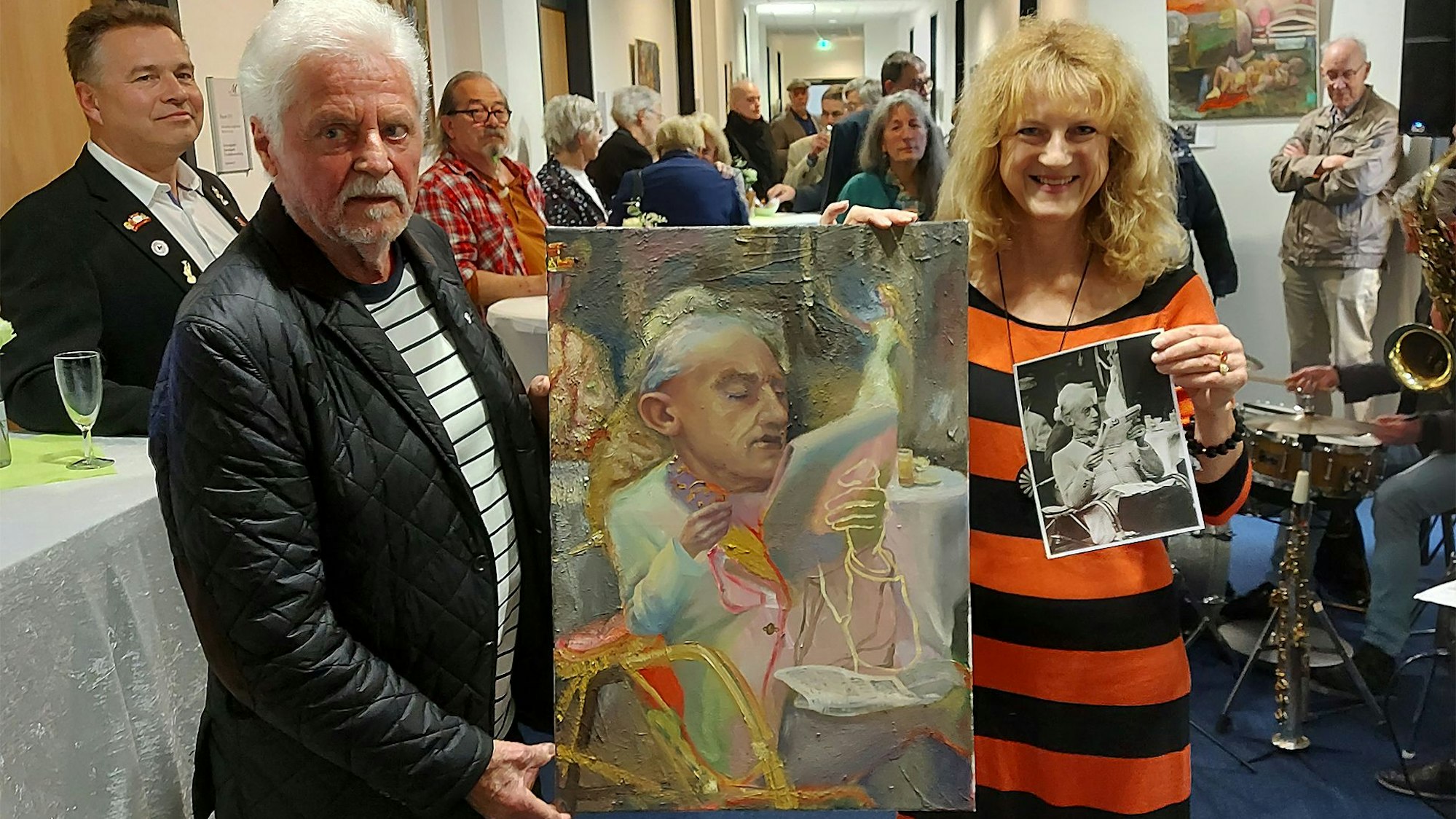 Kruse und Franke halten bei der Ausstellungseröffnung ein Gemälde von Mona Dia.