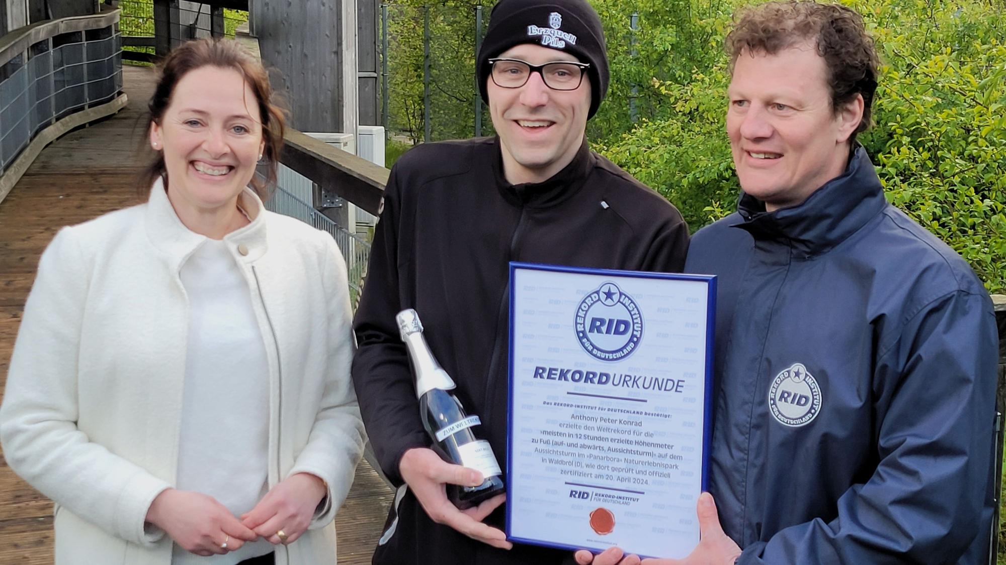 Im Naturerlebnispark Panarbora hat Peter Anthony Konrad (mit Mütze) am 20. April den Weltrekord geschafft, ihm gratulieren Waldbröls Bürgermeisterin Larissa Weber und Wertungsrichter Maik Kaufmann vom Rekord-Institut für Deutschland.