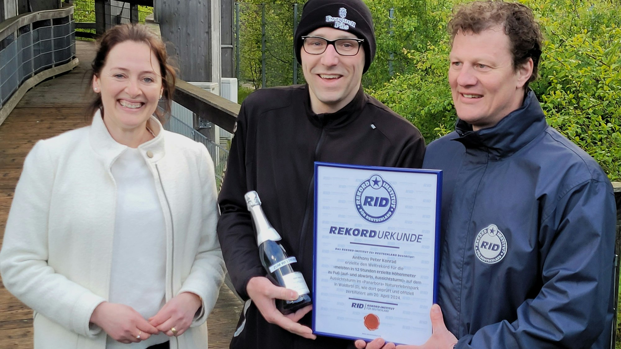 Im Naturerlebnispark Panarbora hat Peter Anthony Konrad (mit Mütze) am 20. April den Weltrekord geschafft, ihm gratulieren Waldbröls Bürgermeisterin Larissa Weber und Wertungsrichter Maik Kaufmann vom Rekord-Institut für Deutschland.