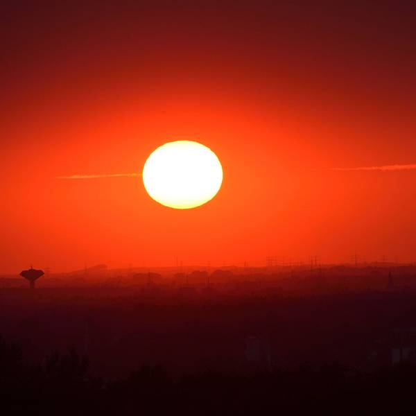 Das Foto zeigt eine glühende Sonne über Bergisch Gladbach und Köln