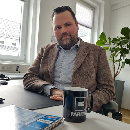 Michael Kehren sitzt an seinem Büroschreibtisch. Vor ihm steht ein schwarzer Kaffeebecher.