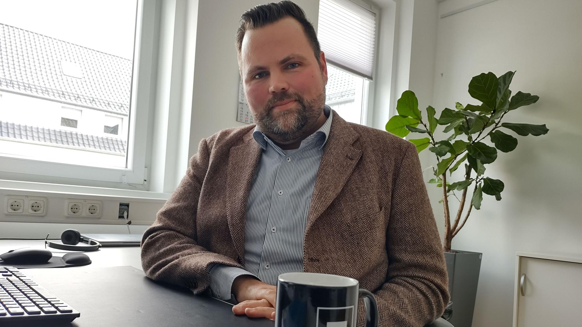 Michael Kehren sitzt an seinem Büroschreibtisch. Vor ihm steht ein schwarzer Kaffeebecher.
