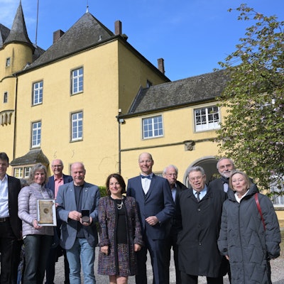 Schloß Strauweiler in Odenthal. Davor eine Gruppe von Menschen.