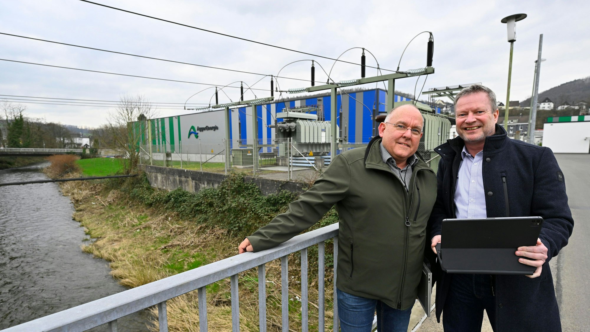 Zwei Männer stehen an einem Werk der Aggerenergie nebeneinander.