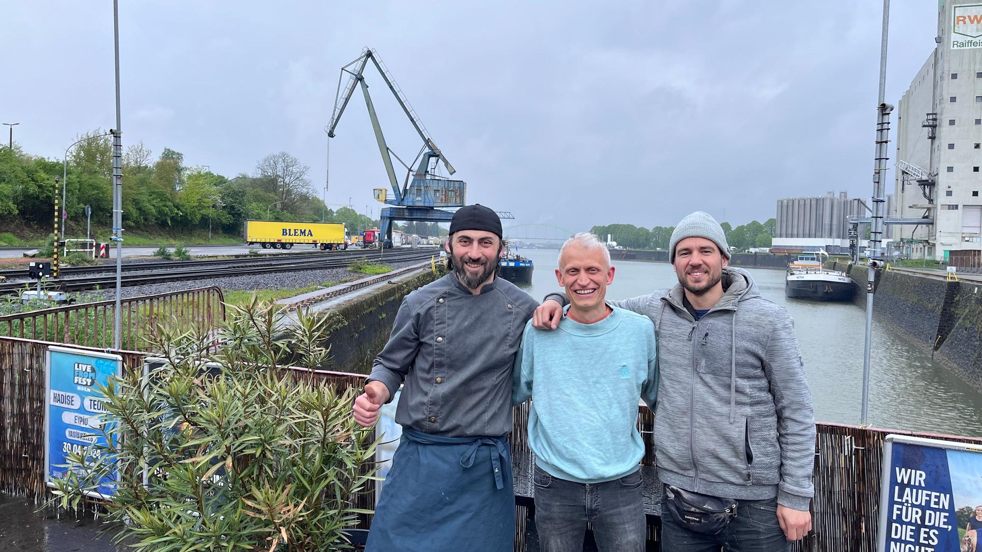 Erkan Karakas, Inhaber der Erkantine, Philip Minettos vom Verein Rosarot und Unterstützer Mario Sroka freuen sich auf das „Vrühlingsfest“ am Niehler Hafen.