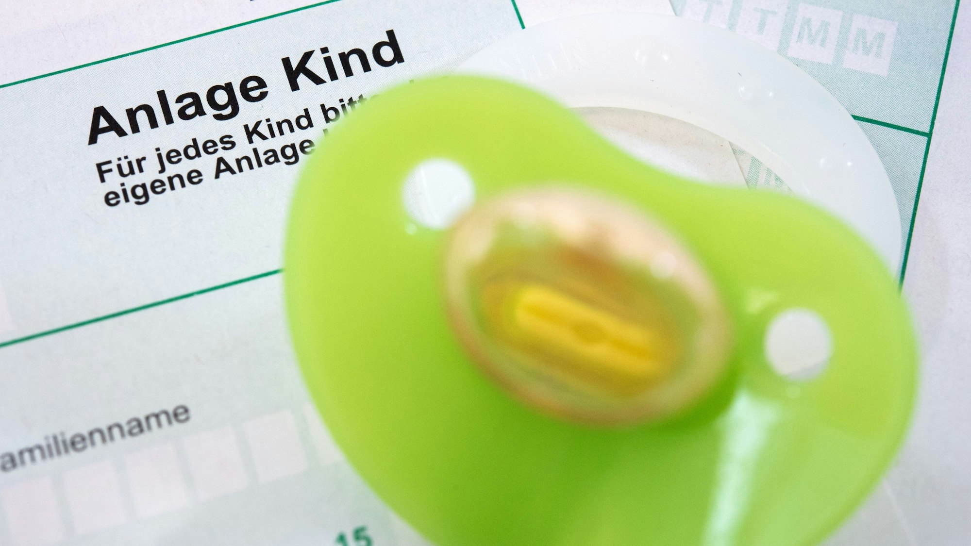Ein Schnuller liegt auf einem Antrag für das Kindergeld