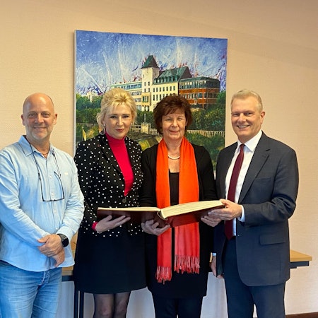 Der Vorstand der aufgelösten Innenstadtgemeinschaft Porz trägt sich ins Ehrenbuch des Stadtbezirks ein.