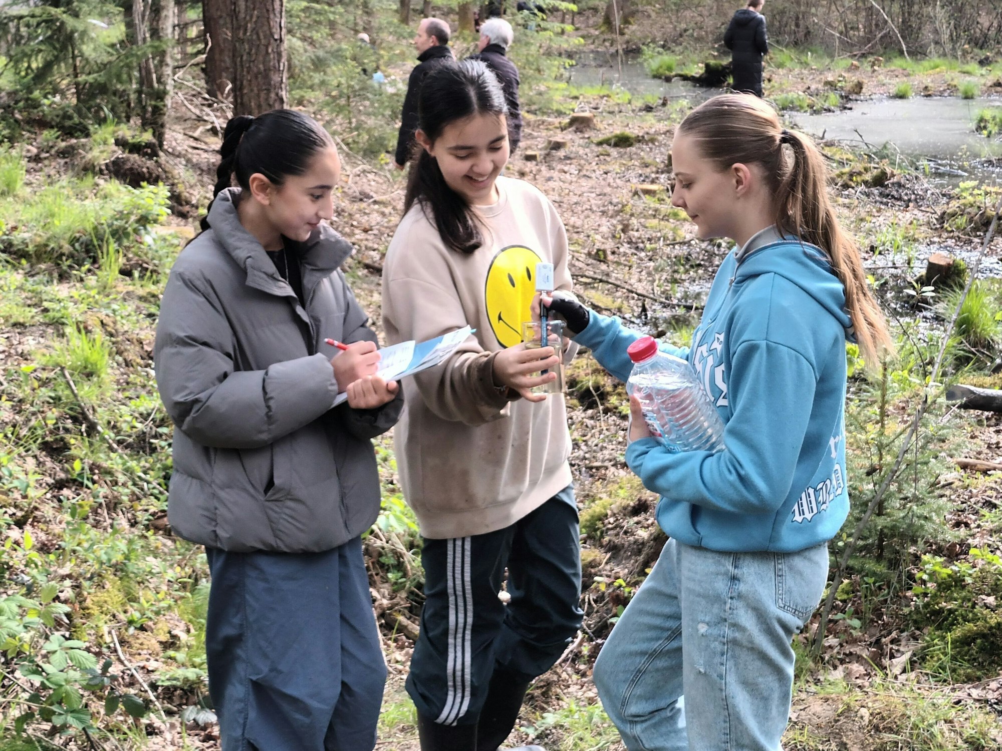 Drei Mädchen mit einer Wasserprobe und einem Messgerät