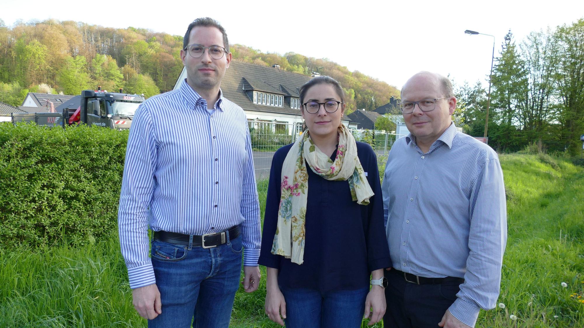 Drei Menschen stehen auf einer Wiese.