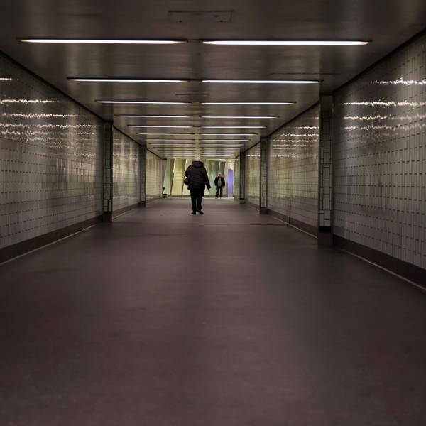 Eine Person geht durch einen langen Tunnel, der nicht hell beleuchtet ist.