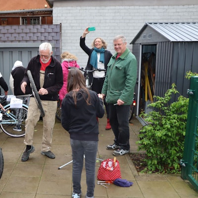 Ehrenamtler vom Repair-Café reparieren zwei Fahrräder. Schülerinnen und Schüler helfen dabei mit.