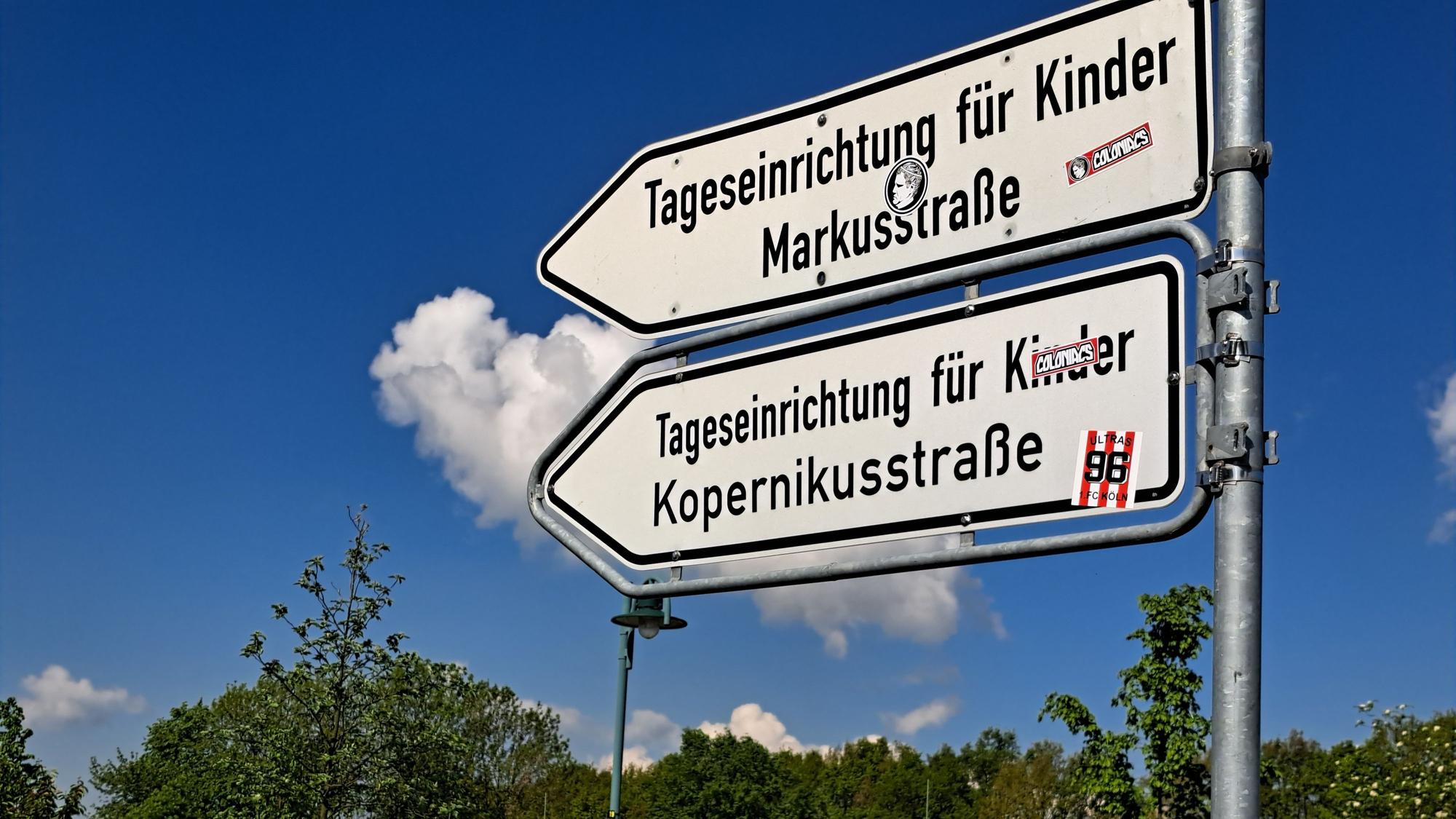 Hinweisschilder an einer Straße. Die Pfeile weisen auf eine Tageseinrichtung für Kinder Markusstraße und die Tageseinrichtung für Kinder Kopernikusstraße hin.