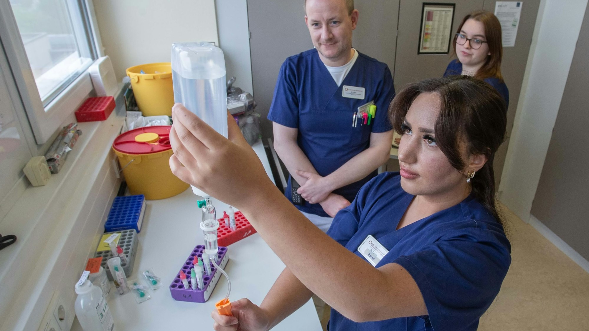 Auch das Vorbereiten von Medikamenten gehört in der Waldbröler Kardiologie zu den Aufgaben der Auszubildenden: Hier macht die Auszubildende Esma Yavuz aus Gummersbach unter Aufsicht von Stationsleiter Daniel Linke eine Infusion fertig. Mitschülerin Zoe Müschenich sieht dabei zu.