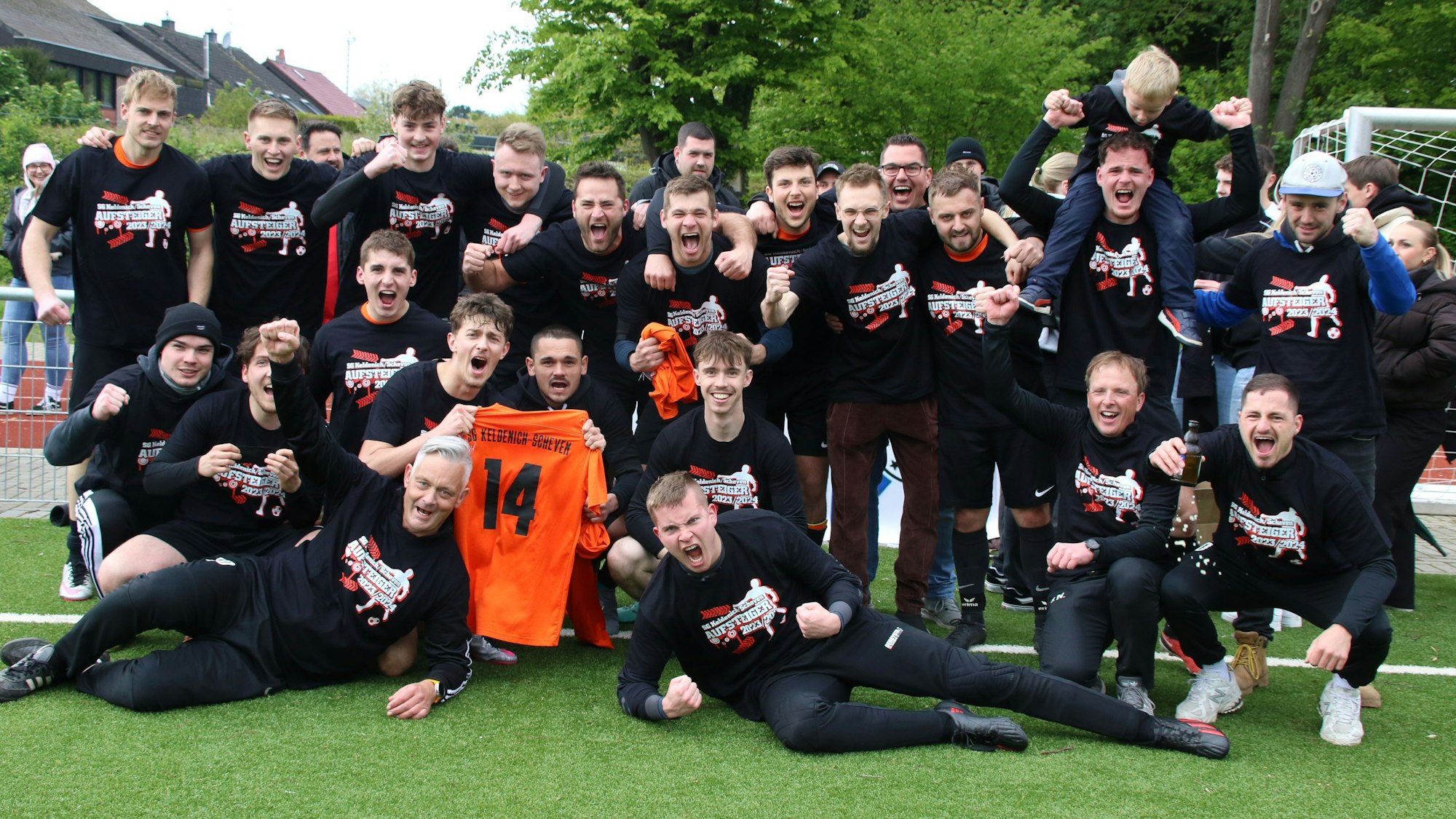 Spieler der SG Keldenich-Scheven jubeln. Zwei halten das Trikot mit der Nr. 14 in die Höhe.