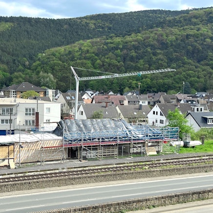 Baustelle zum Abbau des im Stadtteil Walporzheim der Stadt Bad Neuenahr-Ahrweiler gelegenen Bahnhofs. Im Vordergrund verlaufen eine Straße und die Bahnlinie, hinter dem Gebäude steht ein Baukran.