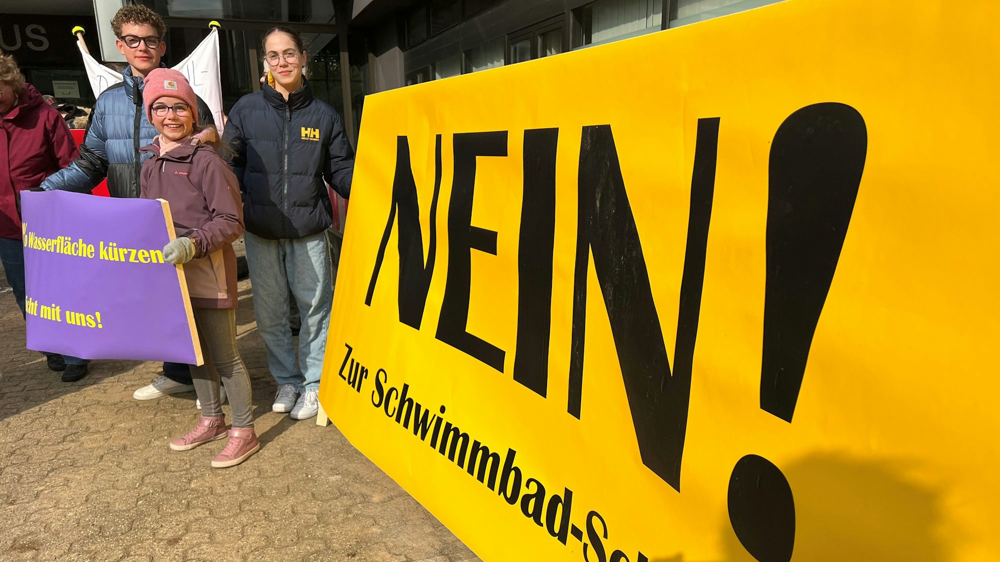 Kinder halten Transparente gegen die geplante Schließung des Schwimmbads hoch.
