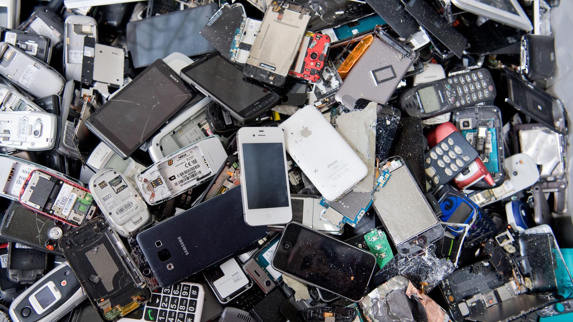 Alte Handys und Smartphones liegen in einem Container, ehe sie geschreddert werden.
