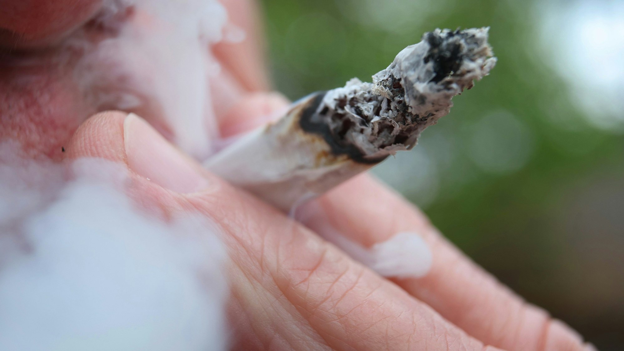 Das Symbolbild zeigt, wie ein Mann einen Joint raucht.