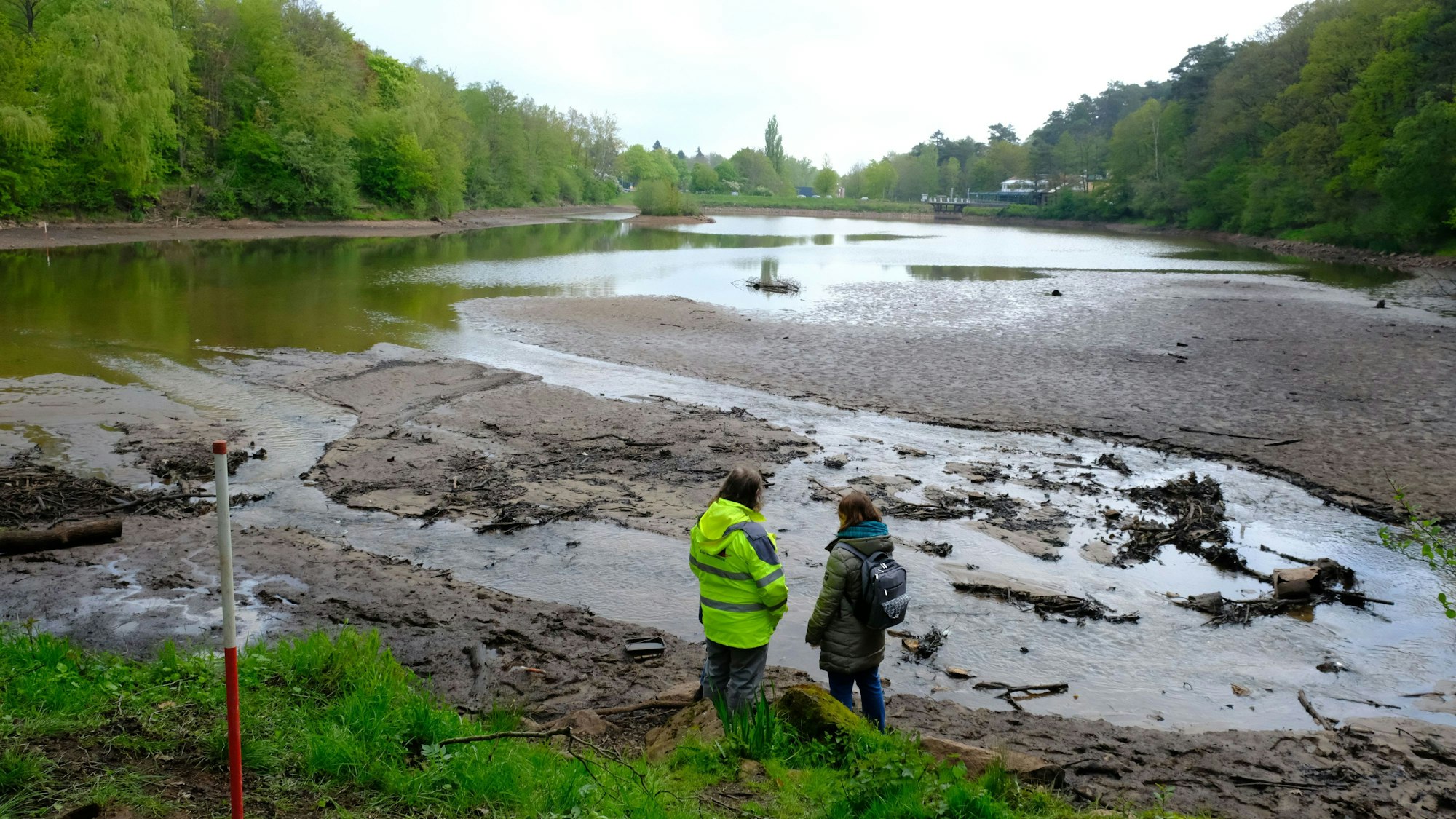 Der Kommerner Mühlensees hat kaum noch Wasser, viele Stellen treten inselartig hervor. Zwei Personen stehen am Rand.