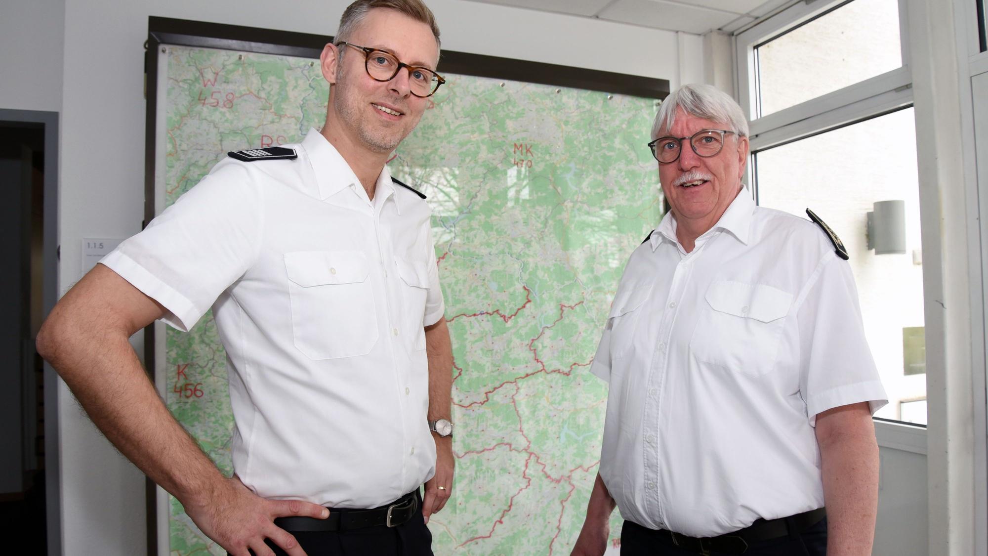 Der neue Kreisbrandmeister und scheidende Kreisbrandmeister Wilfried Fischer des Oberbergischen Kreises stehen vor einer Kreiskarte nebeneinander.