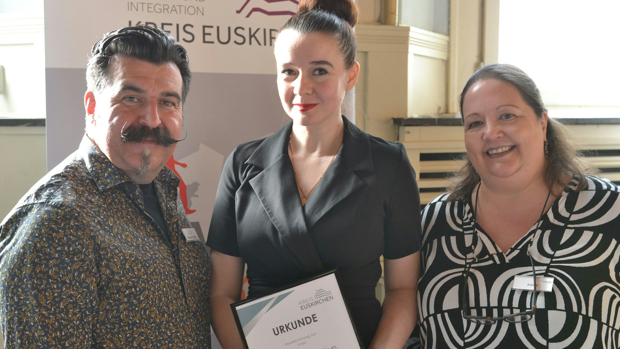 Natalia Skakun hält ihre Urkunde in den Händen, links von ihr steht Roland Kuhlen, rechts Stefanie Asbeck.