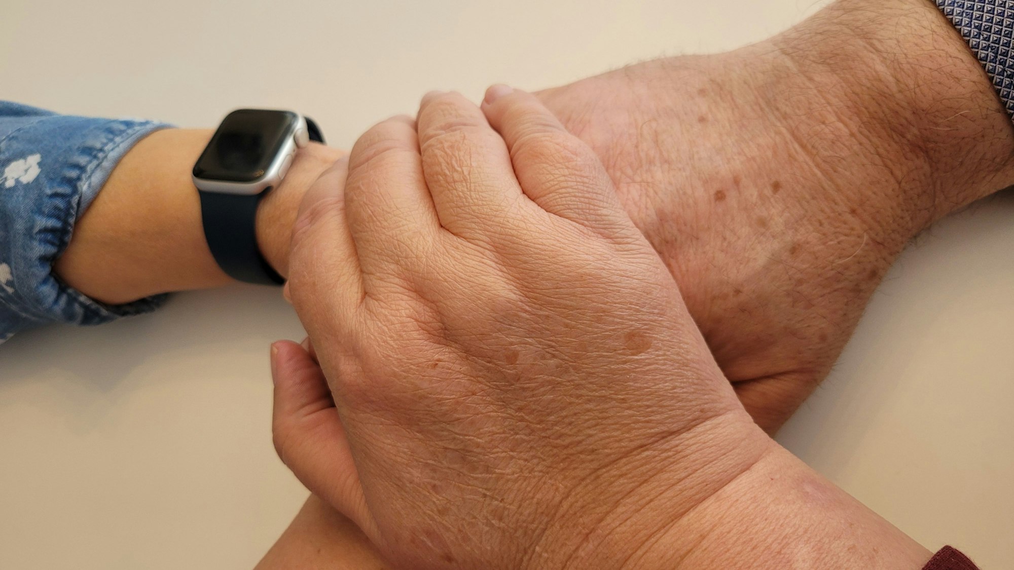 Das Foto zeigt drei Hände, die sich berühren.