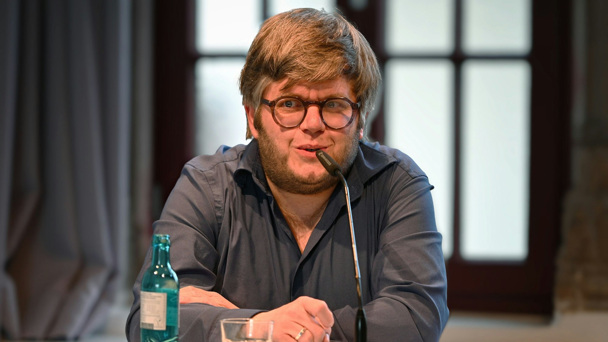 Martin Becker sitzt vor einem Mikrofon.