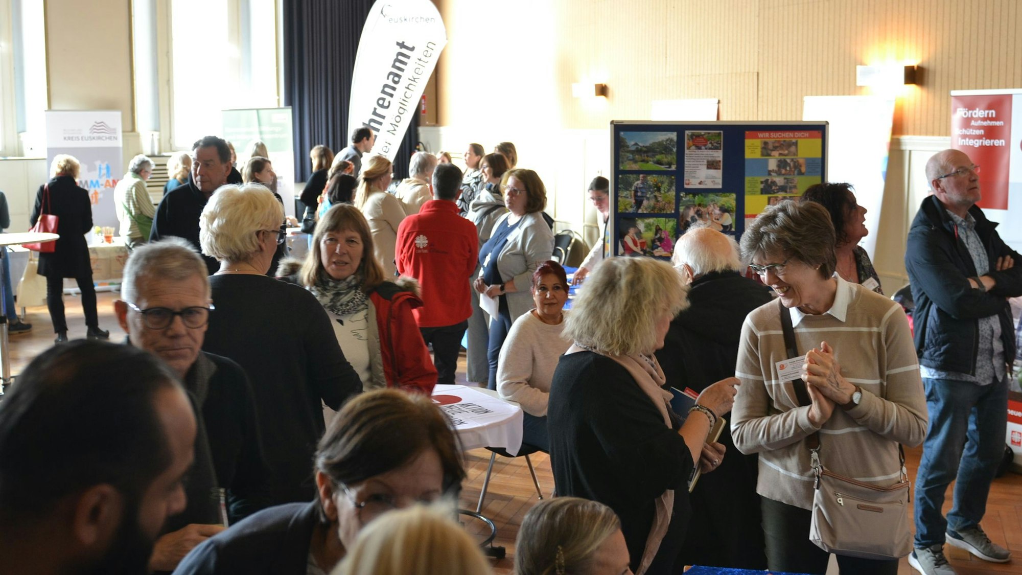 Menschen stehen im Gespräch vor Stellwänden.