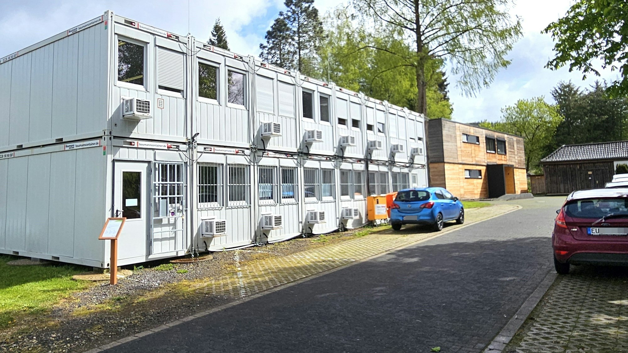 Blick auf die Stahlcontainer mit den Holzmodulen im Hintergrund.