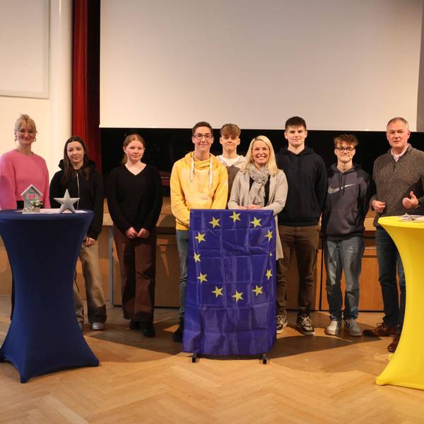 Die Teilnehmer haben sich an Stehtischen gruppiert.