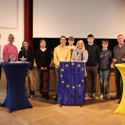 Die Teilnehmer haben sich an Stehtischen gruppiert.