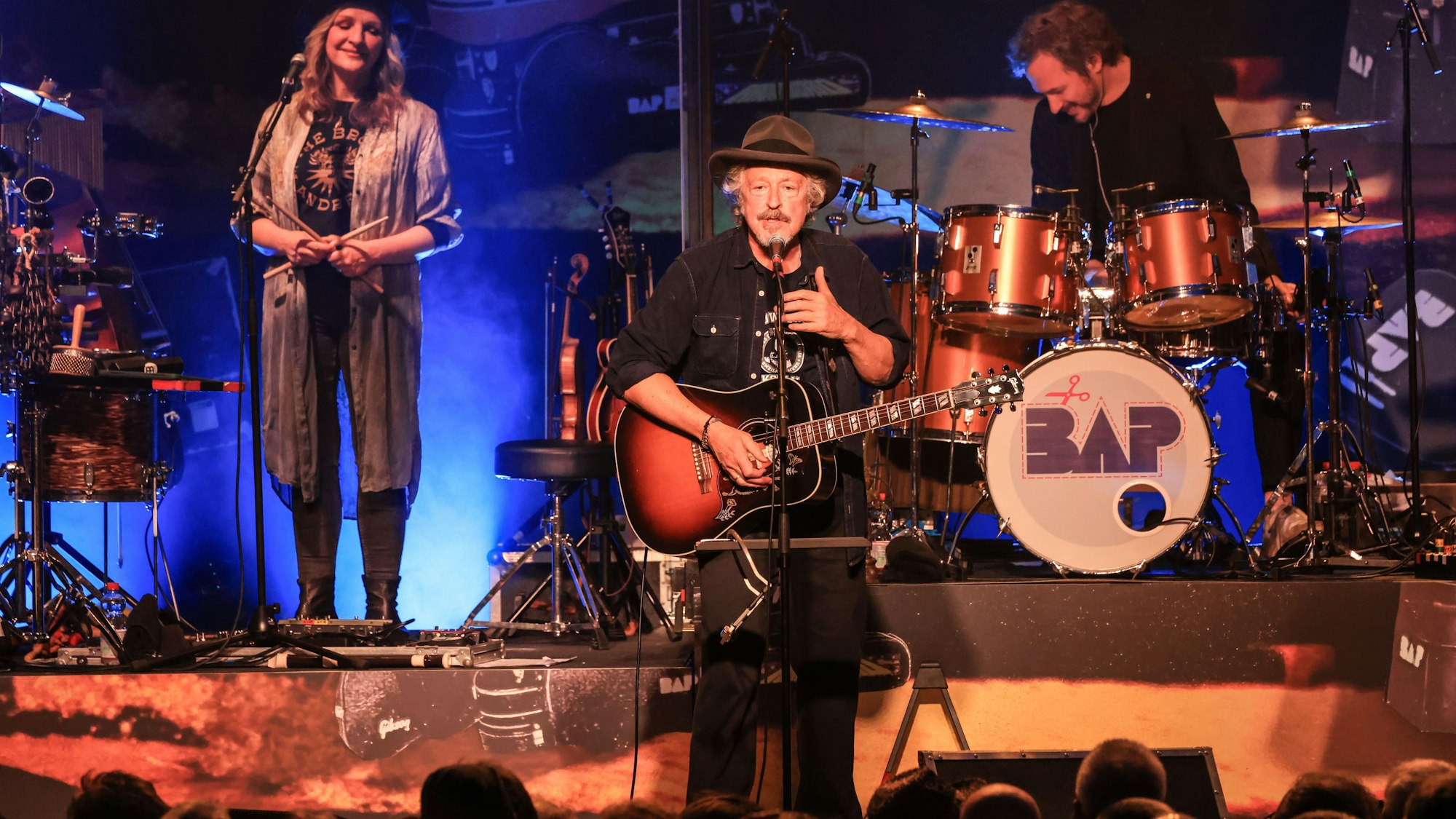 Wolfgang Niedecken (M) steht mit Anne de Wolff (l) und Sönke Reich (r) auf der Bühne.
