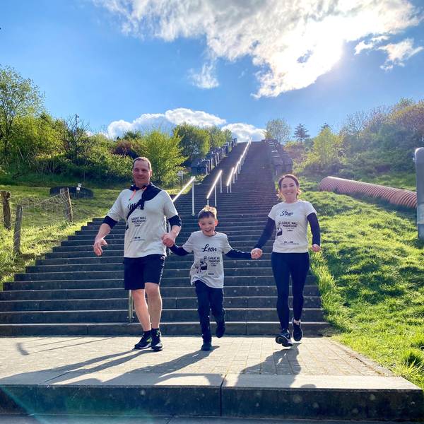 Leon Barth und seine Eltern Stefanie und Marc laufen Hand in Hand eine Treppe herunter.