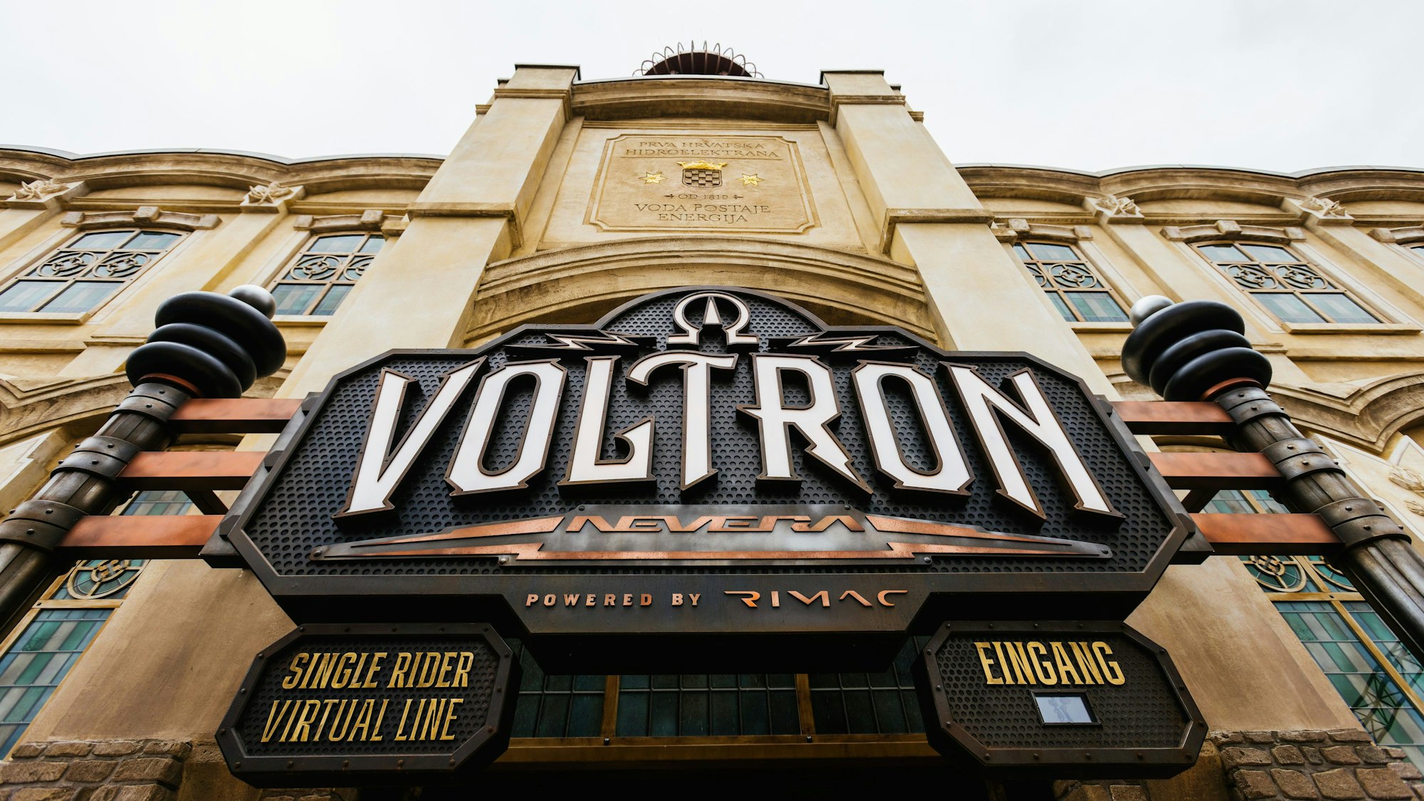 Das Logo der Achterbahn Voltron Nevera ist über dem Eingang zum Bahnhofsgebäude zu sehen.