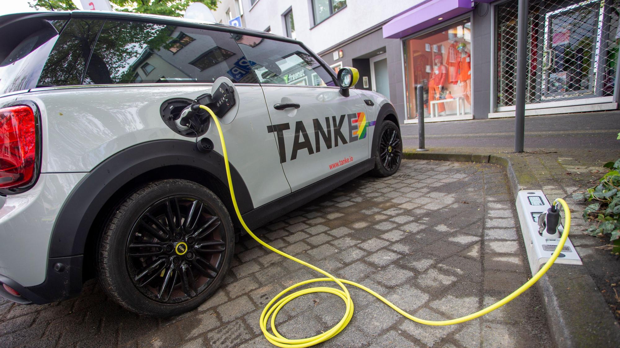 Ein E-Auto wird an einem Ladepunkt aufgeladen, der in einem Bordstein integriert ist.