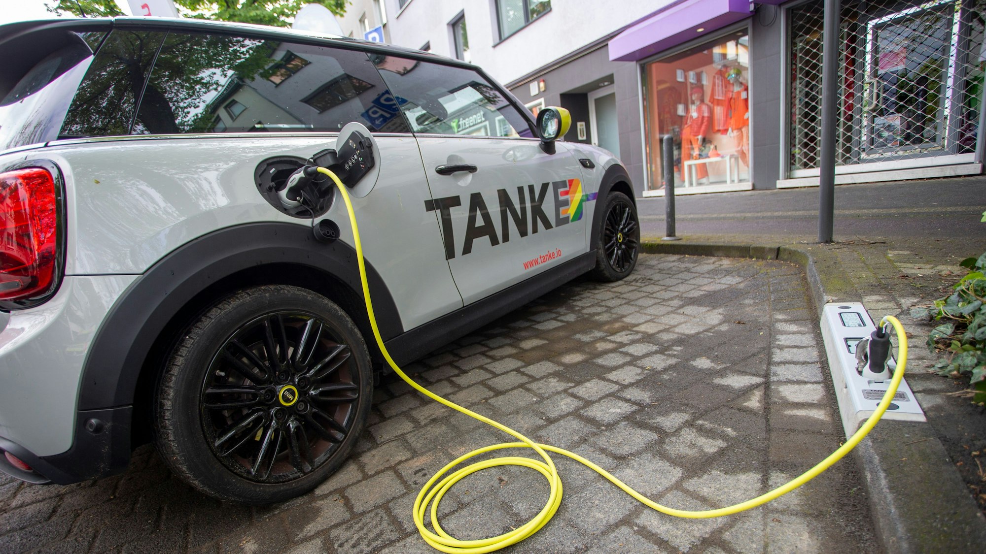 Ein E-Auto wird an einem Ladepunkt aufgeladen, der in einem Bordstein integriert ist.