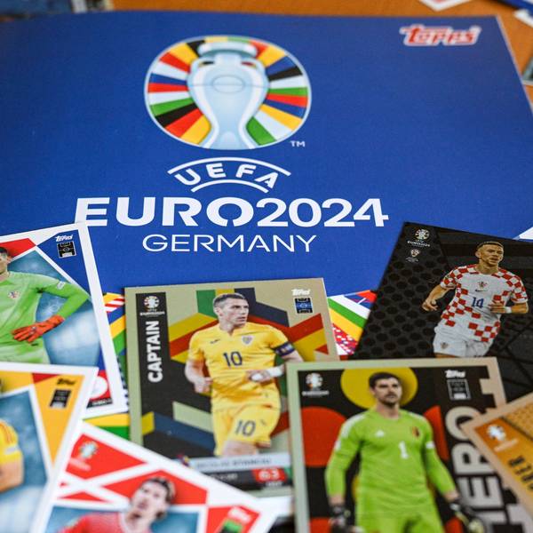 Das Sammelalbum Topps und einige Sticker zum Einkleben liegen zusammen auf einem Tisch.