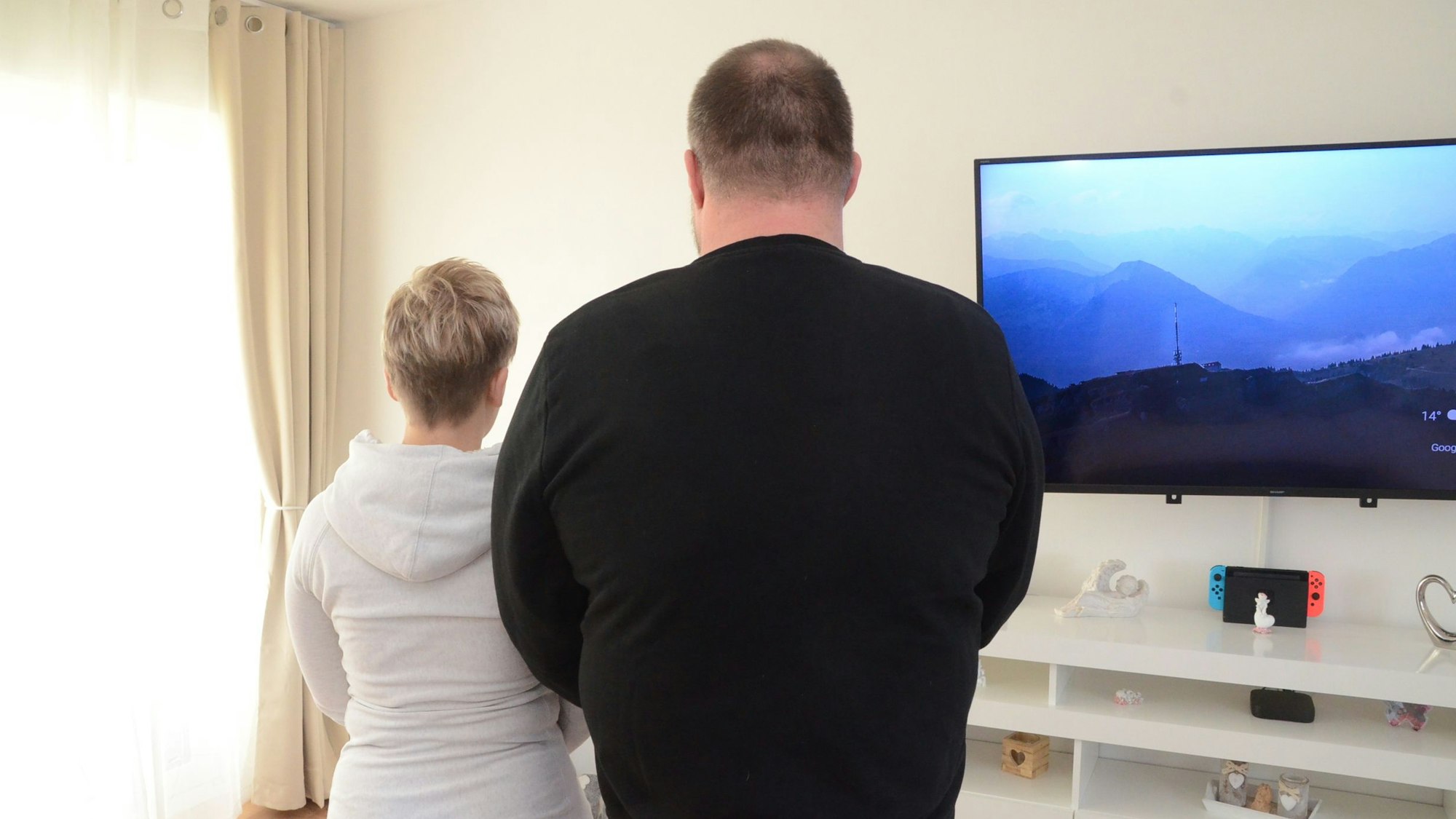 Ein Mann und eine Frau blicken in Richtung einer Wand.