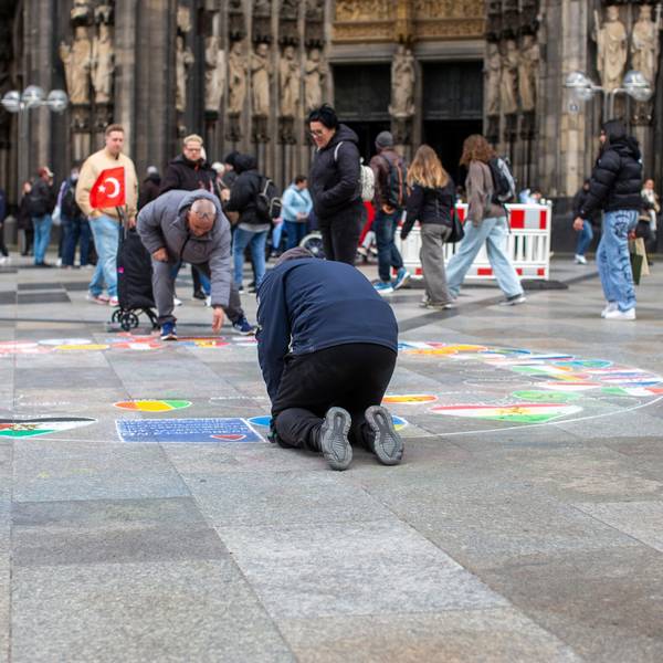 Ein Flaggenmaler vor dem Kölner Dom.