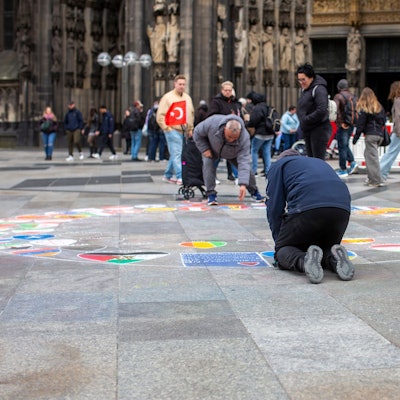 Ein Flaggenmaler vor dem Kölner Dom.