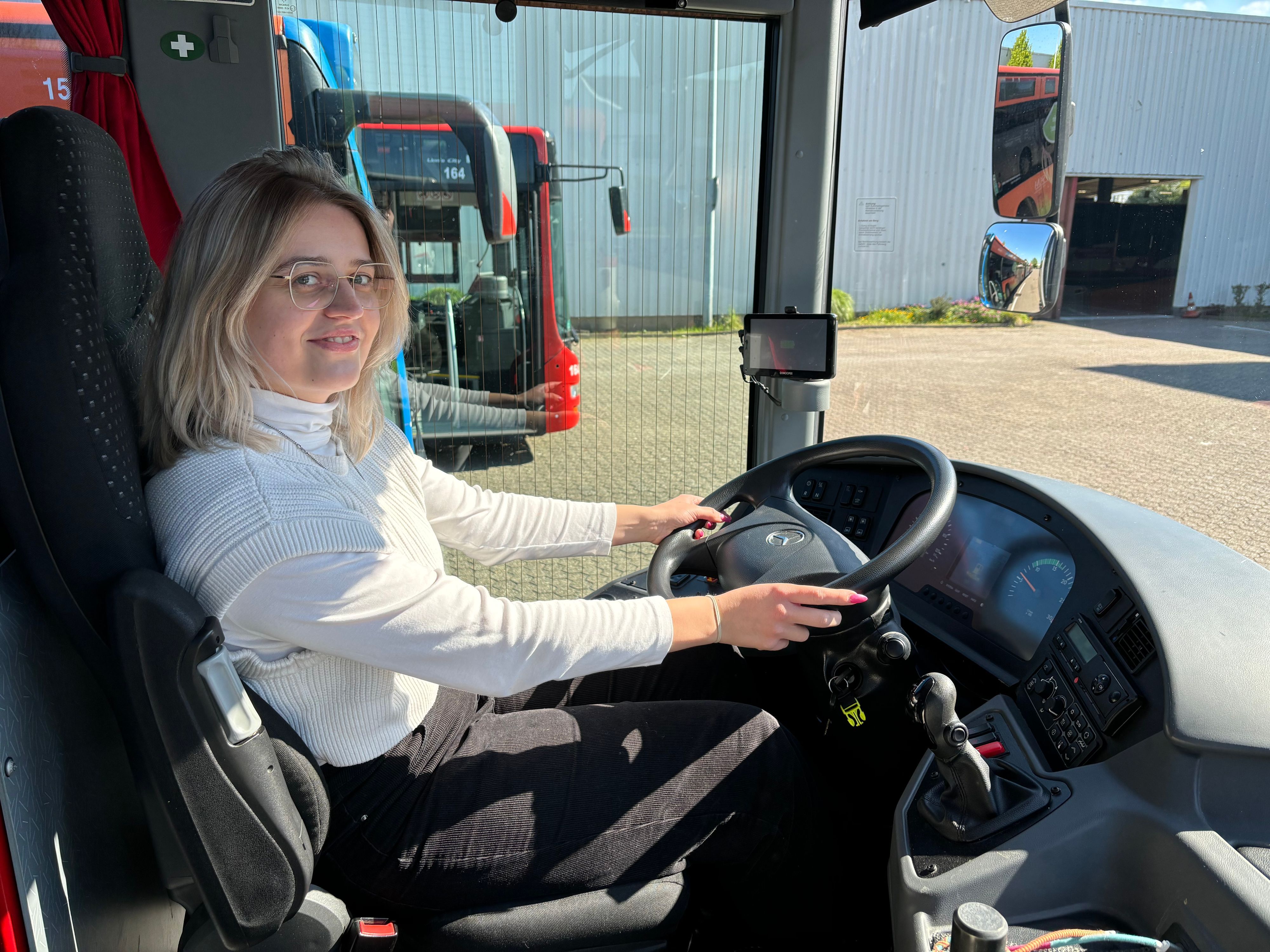 Eine Frau sitzt an dem Lenkrad eines Busses.