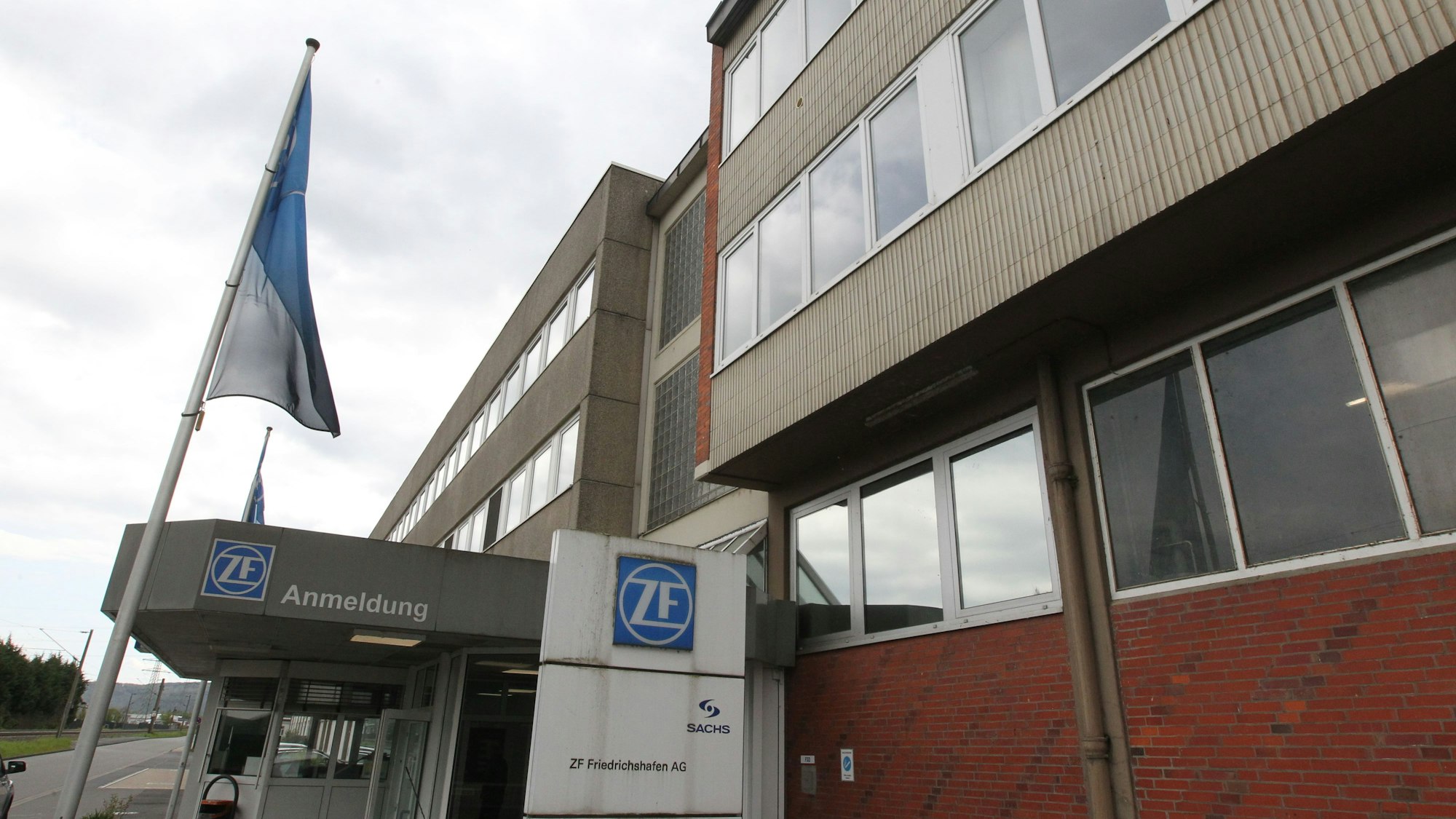 Ein altes Gebäude aus Klinker und Beton, vor dem EIngang mit dem ZF-Logo weht eine Fahne.