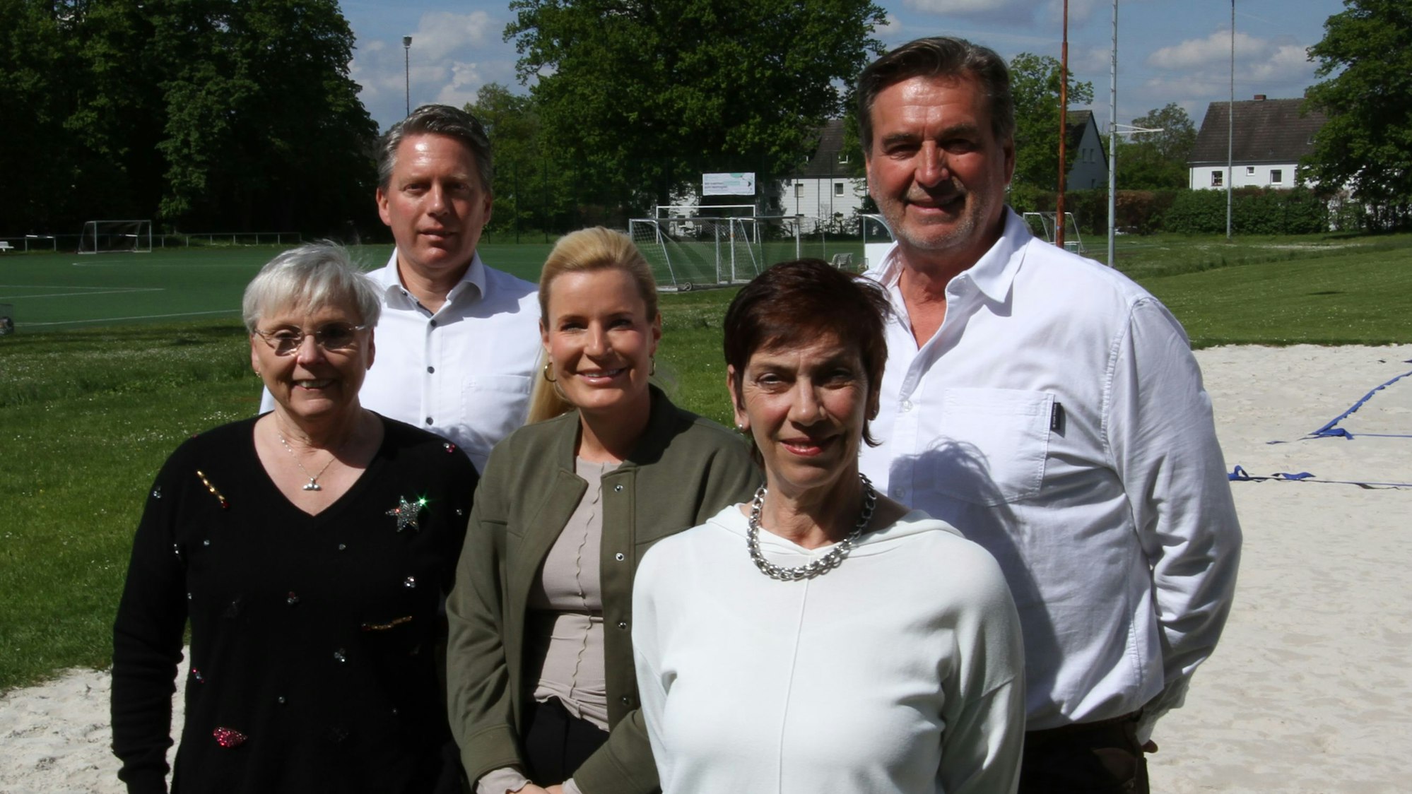 Drei Frauen und zwei Männer an einem Sportplatz