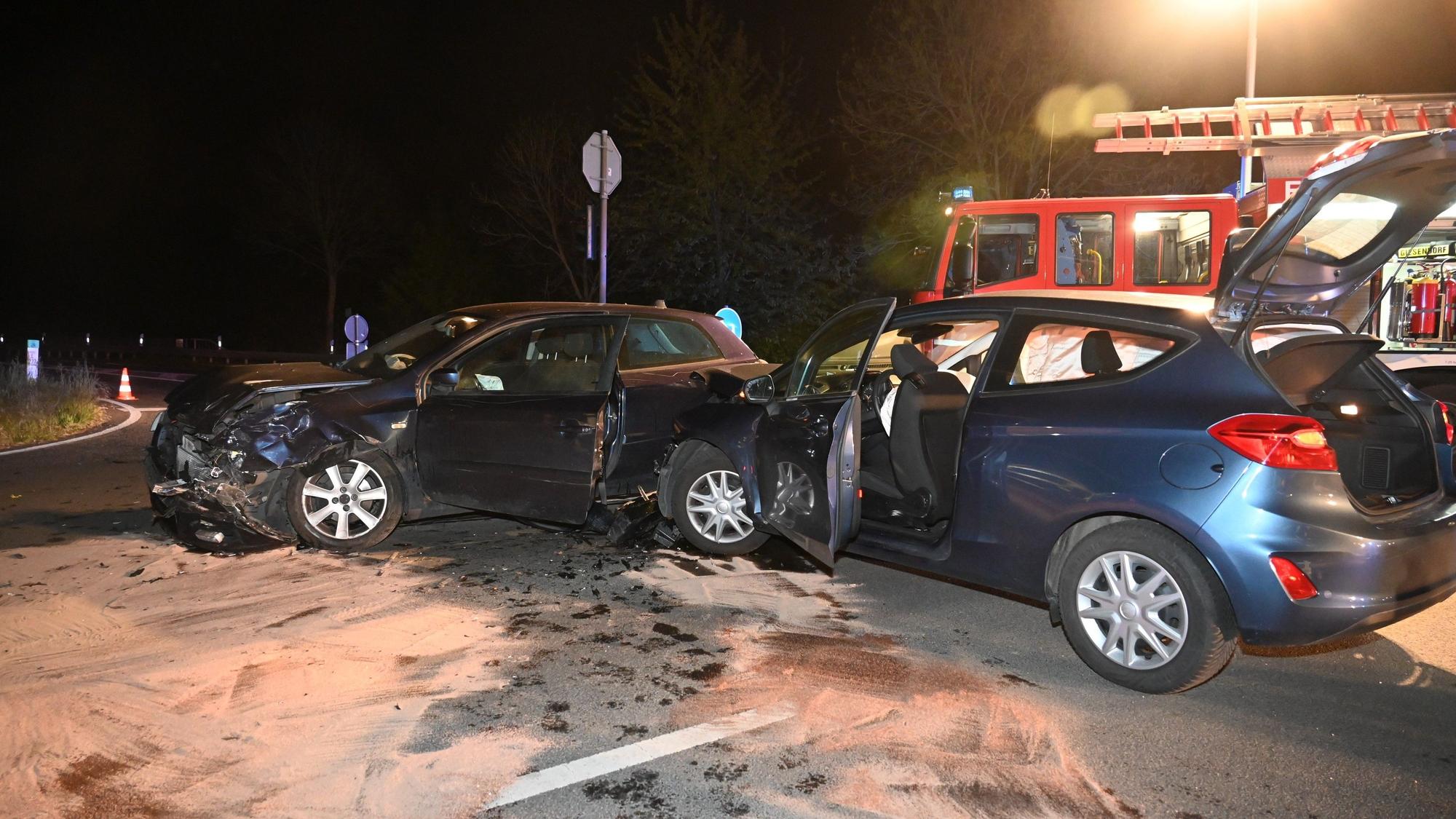 Zwei beschädigte Autos. Im Hintergrund ein Einsatzfahrzeug der Feuerwehr.