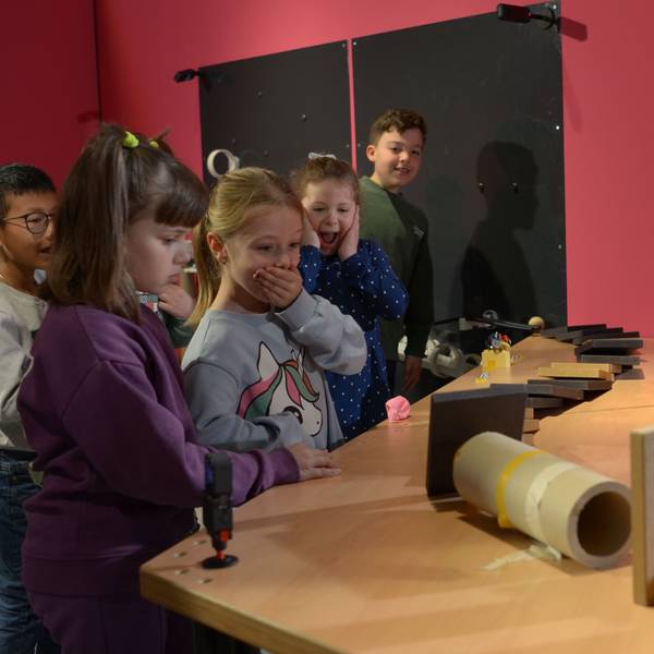 Mädchen und Jungen beobachten, wie eine Kugel durch den Parcours läuft. Die Spannung ist an ihren Gesichtern abzulesen.