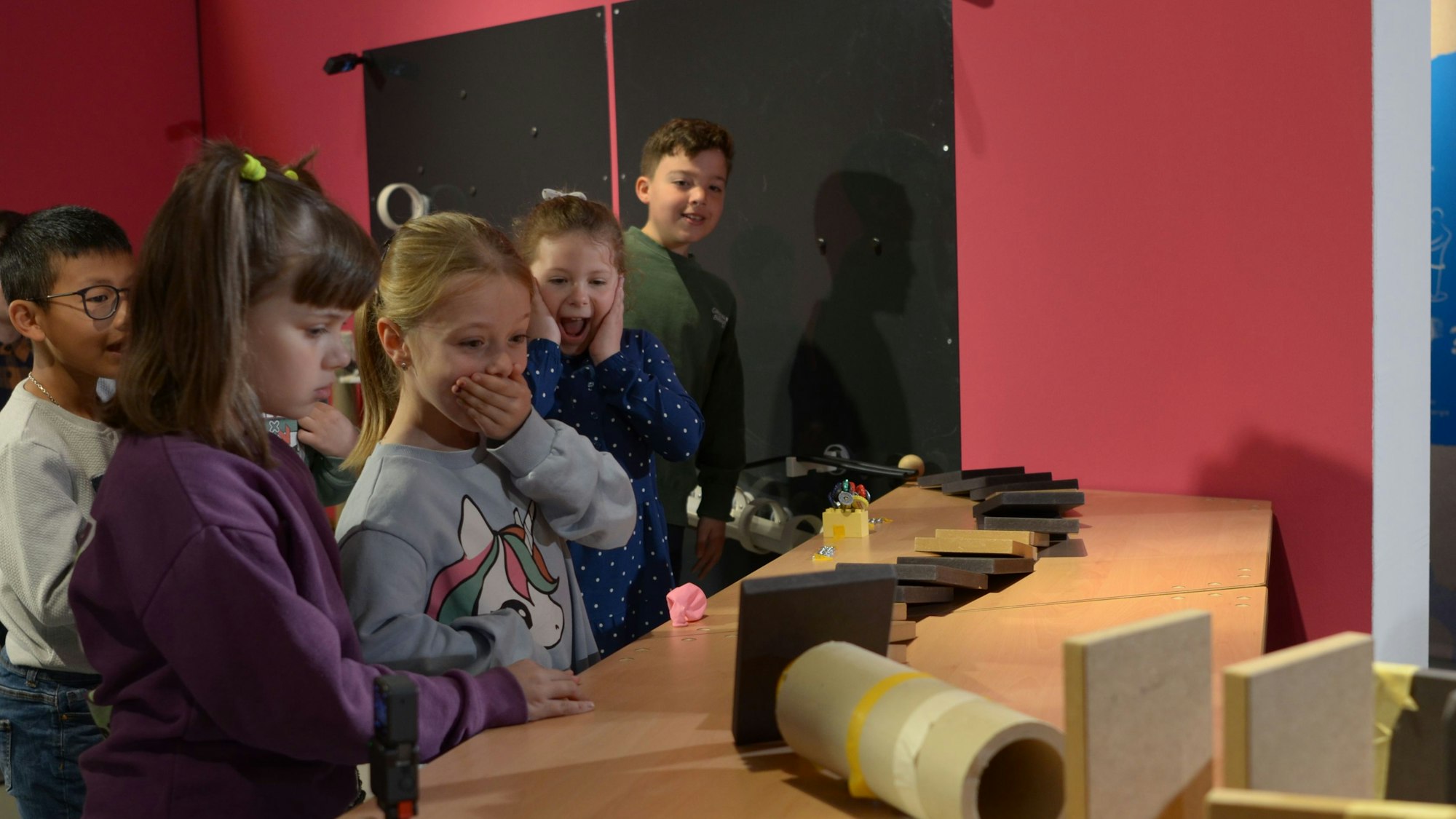 Mädchen und Jungen beobachten, wie eine Kugel durch den Parcours läuft. Die Spannung ist an ihren Gesichtern abzulesen.