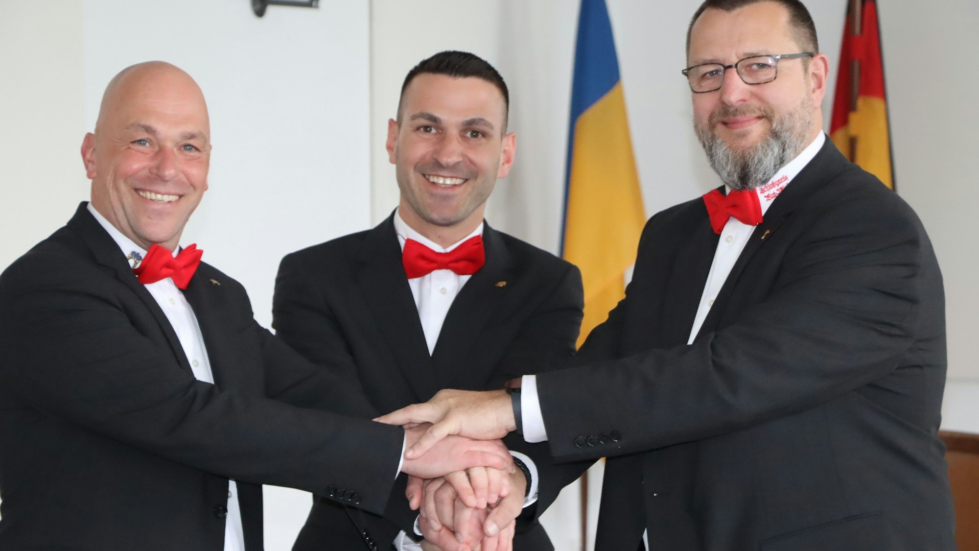 Zu sehen ist das designierte Dreigestirn, das die Hände übereinander hält.