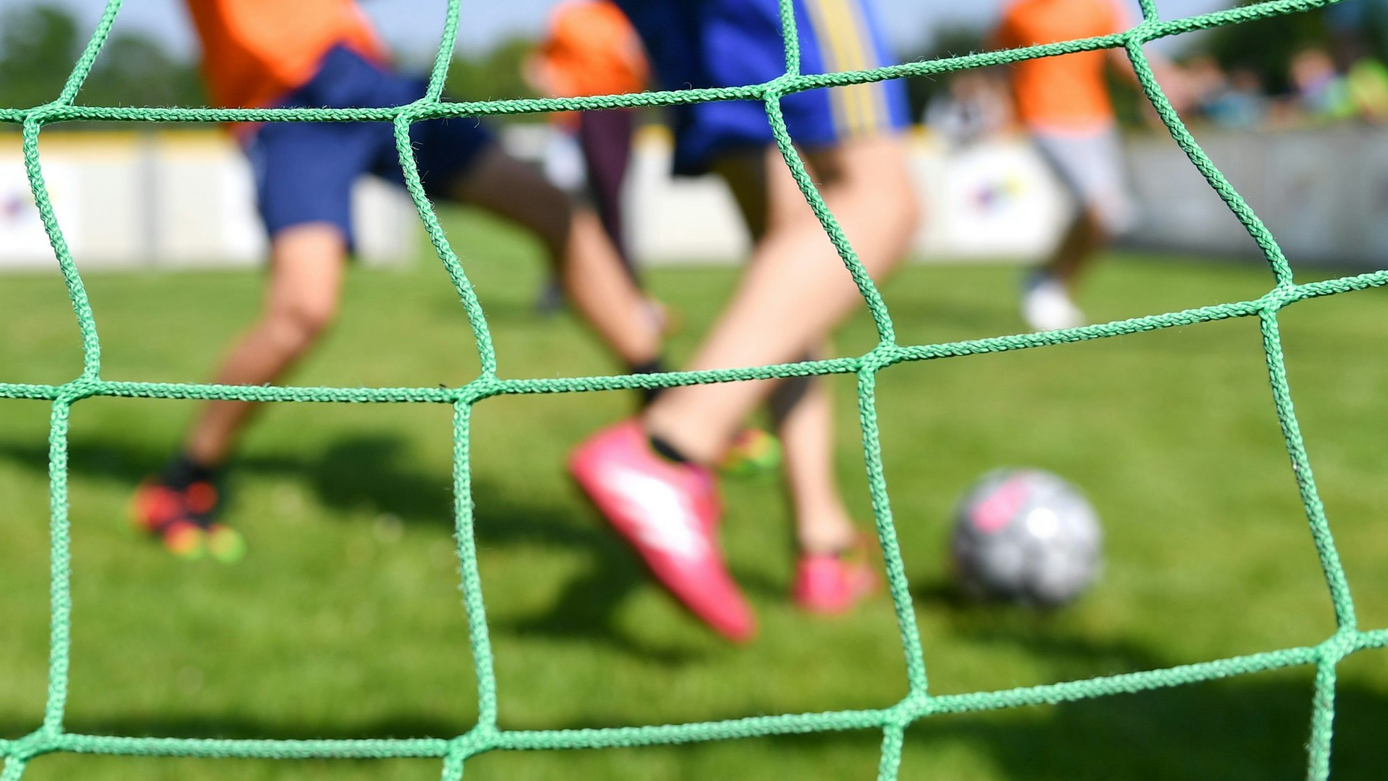 Fußballspielende Kinder durch ein Tornetz fotografiert