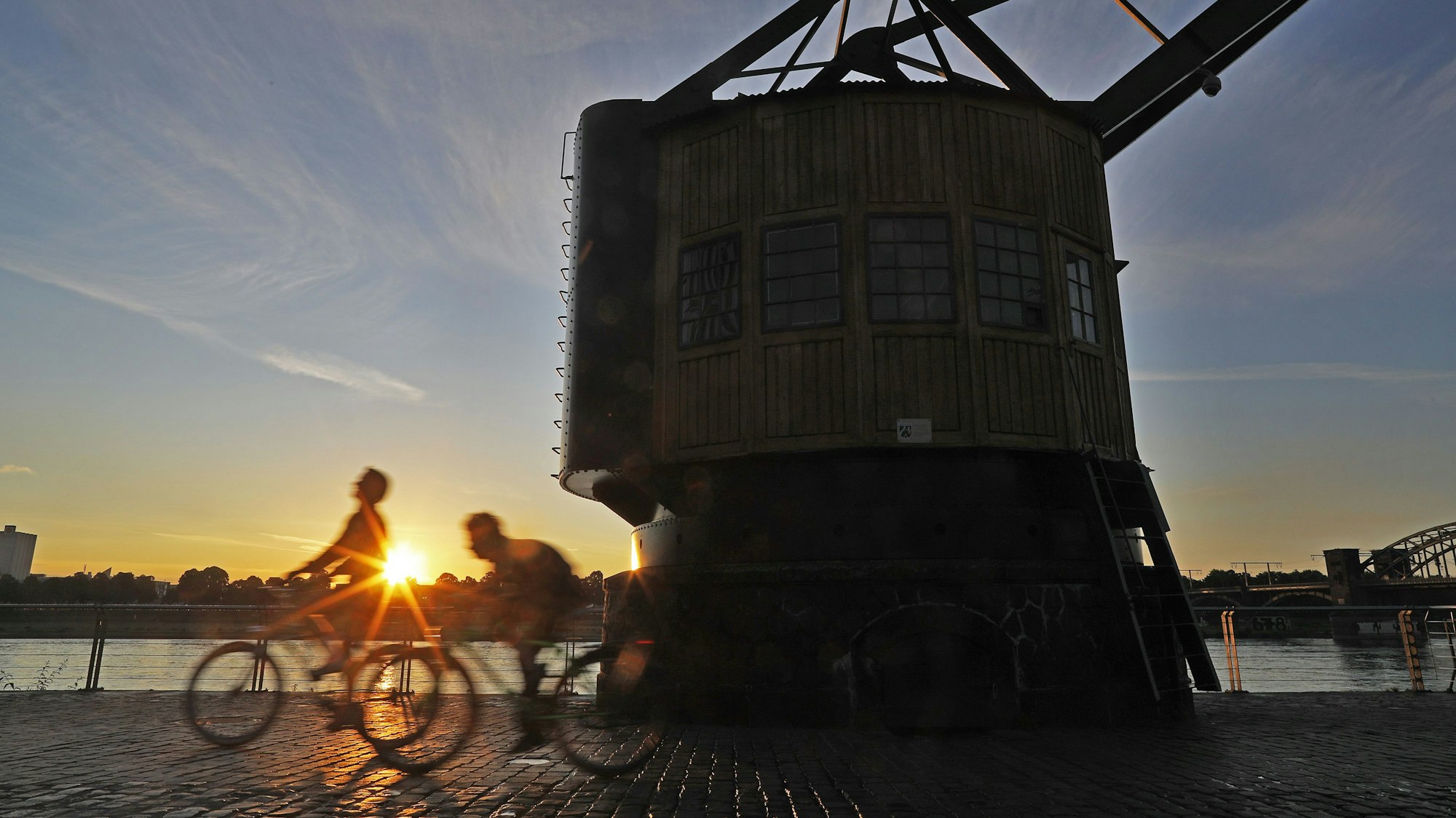 Radfahrer fahren in der Morgensonne am Rhein entlang