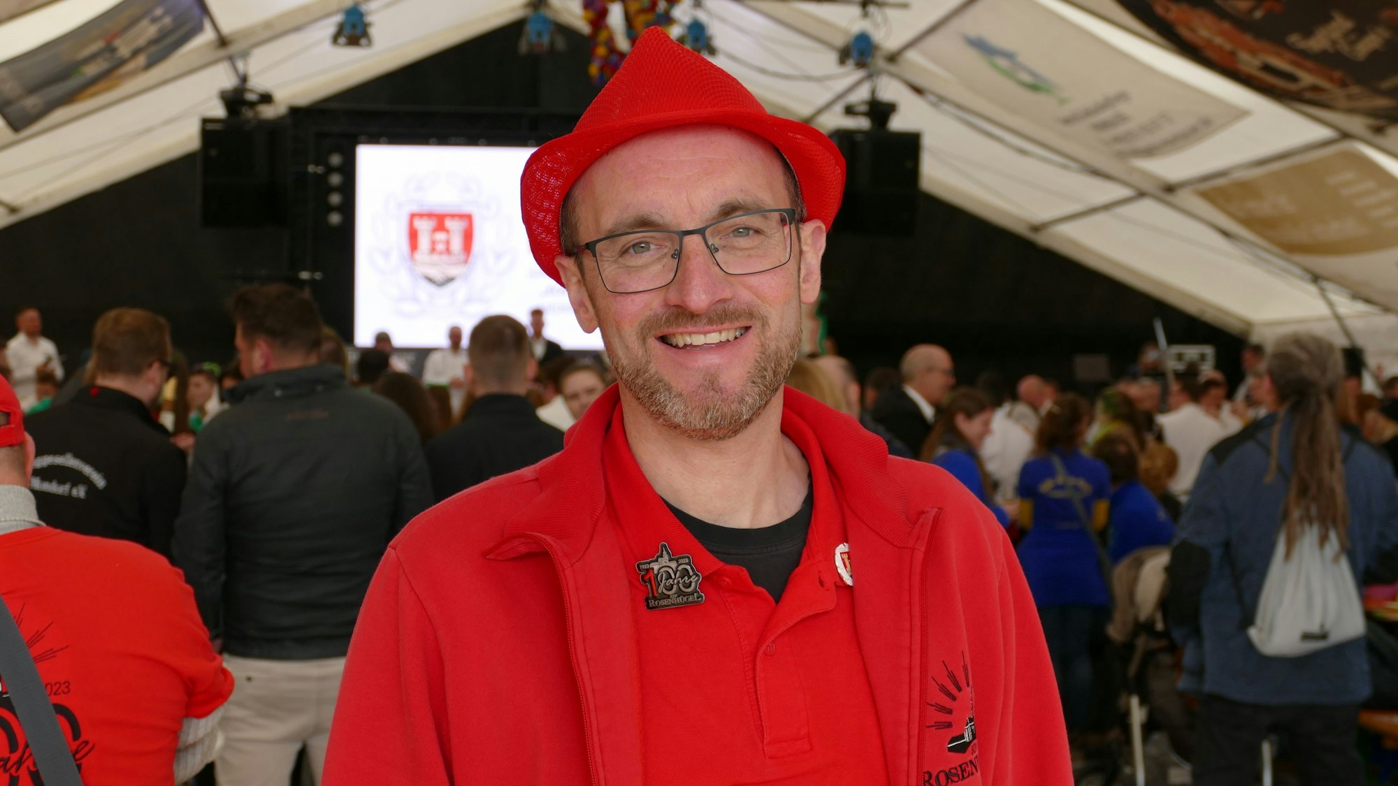 Ein Mann mit rotem Hut blickt in die Kamera.